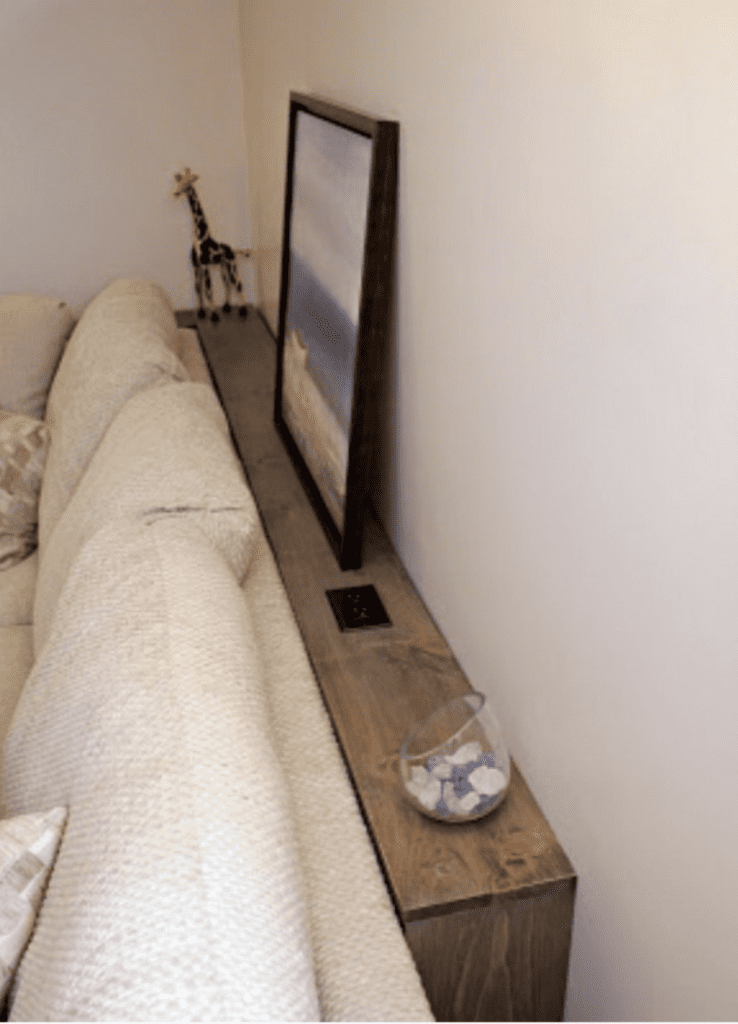 A sleek console table with drawers and decorative items placed behind a sofa.